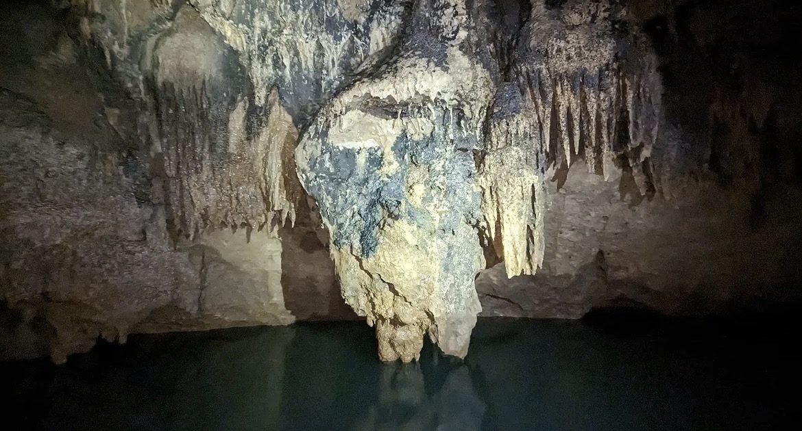 ATM Cave Tour participants wearing helmets and headlamps safely navigating underground passages in Belize